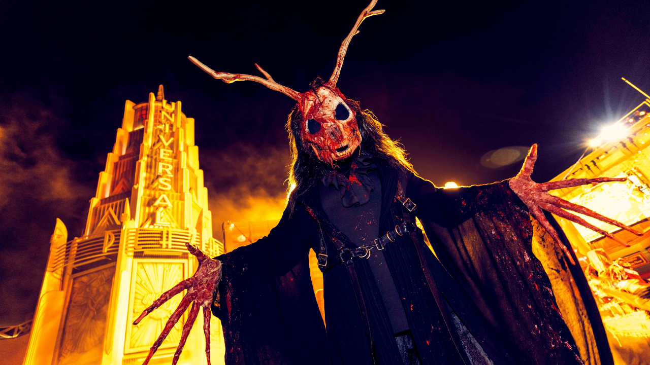 Scare actor with horns and long fingers in from of Universal Studios building