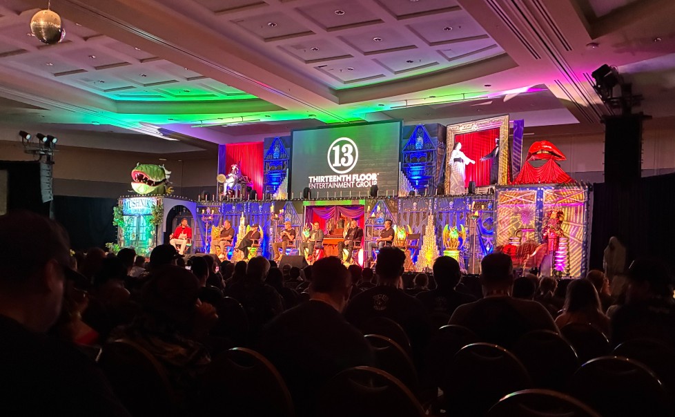 image of the 13th Floor Entertainment Group panel at Midsummer Scream from sitting in the crowd. Speakers are sitting on the stage with festive Halloween decor and lighting